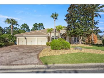 Beautiful home with three car garage, lush landscaping, and brick paver driveway at 17819 Sw 61St Lane Rd, Dunnellon, FL 34432