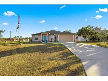 One-story home with teal door, driveway and American flag at 6560 Sw 129Th St, Ocala, FL 34473