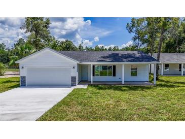 Newly constructed home with a white exterior, gray stone accents, and a covered porch at 13024 Ne 6 Pl, Silver Springs, FL 34488