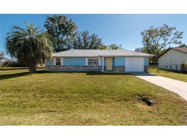 Light blue house with a white garage door and well-manicured lawn at 24 Banyan Dr, Ocala, FL 34472