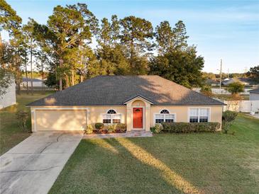 Single-story house with a red door, attached garage, and well-maintained lawn at 3011 Se 46Th Ave, Ocala, FL 34480