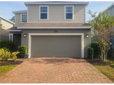 Two-story house with gray siding, brick driveway, and a two-car garage at 1609 Chelsea Manor Cir, Deland, FL 32724