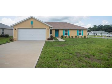 Tan house with teal shutters, white garage door, and a well-maintained lawn at 349 Marion Oaks Mnr, Ocala, FL 34473