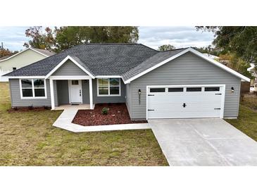 Gray house with white garage door and landscaping at 8952 Se 156Th St, Summerfield, FL 34491