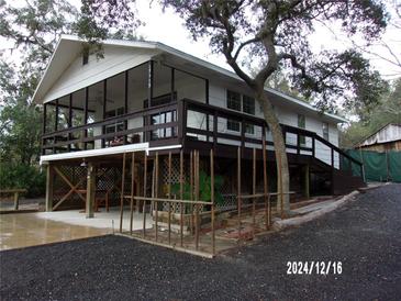 Elevated home with wraparound porch, screened deck, and spacious parking area at 17935 Se 10Th Pl, Silver Springs, FL 34488