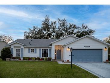White house with blue garage door, landscaping, and a spacious lawn at 4707 River Ridge Dr, Leesburg, FL 34748