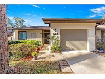 Tan house with brown roof, landscaped yard, and attached garage at 1610 Ne 38Th Ter, Ocala, FL 34470