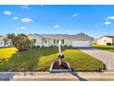 Single-story home with a paved driveway, well-manicured lawn, and mature landscaping at 9862 Se 179Th Pl, Summerfield, FL 34491