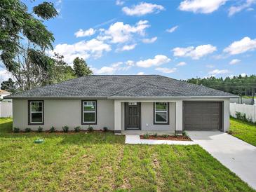 Newly constructed single-story home with gray siding, dark gray garage door, and a well-manicured lawn at 13457 Sw 107Th Pl, Dunnellon, FL 34432