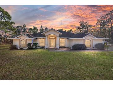 Single-story home with columns and a landscaped yard under a sunset sky at 13780 Sw 78Th Pl, Dunnellon, FL 34432