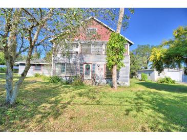 Two-story house with gray siding, red trim, and a spacious yard at 6121 County Road 547 N, Davenport, FL 33837