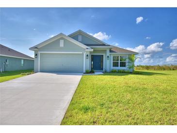 Newly constructed home with a light green exterior, two-car garage, and a well-manicured lawn at 4073 Tullamore Ln, Auburndale, FL 33823