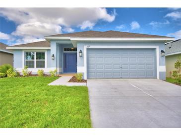 Single-story home with gray exterior, two-car garage, and landscaped lawn at 1218 Tagliamento Ln, Haines City, FL 33844