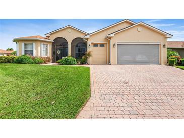 Tan house with a brick driveway and screened porch at 4496 Strathmore Dr, Lake Wales, FL 33859