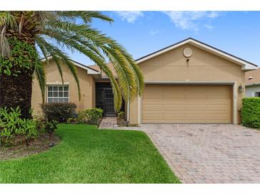 Tan house with a palm tree, brick driveway and two car garage at 4432 Waterford Dr, Lake Wales, FL 33859