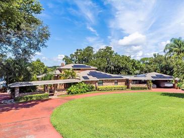 Brick home with solar panels, circular driveway and lush landscaping at 121 E Lake Summit Dr, Winter Haven, FL 33884