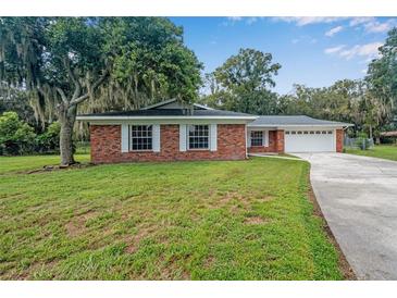 Brick ranch home with a two-car garage and spacious lawn at 3050 Cross Fox Dr, Mulberry, FL 33860