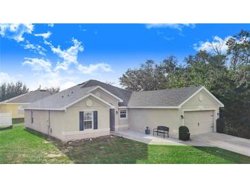 Tan house with a two-car garage and green lawn at 230 Grouper Ct, Poinciana, FL 34759