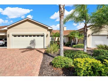 Tan house with two-car garage and landscaped yard at 1613 Linz Ct, Winter Haven, FL 33884