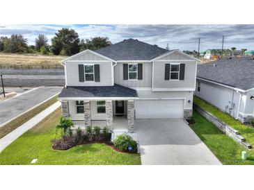 Two-story house with gray siding, stone accents, and a two-car garage at 9660 Westside Hills Dr, Davenport, FL 33896