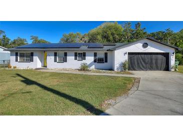 White brick ranch house with solar panels, attached garage, and landscaped lawn at 1610 Meadow Ne Ln, Winter Haven, FL 33881