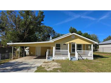 A charming yellow house with a white porch and carport at 616 Pine St, Auburndale, FL 33823