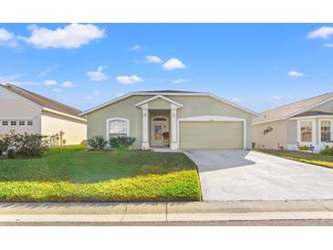 Charming green one-story home with a welcoming front porch and attached two-car garage at 221 Prather Dr, Davenport, FL 33837