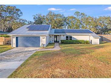 House exterior featuring a metal roof, solar panels, and a landscaped lawn at 4210 Old Colony Rd, Mulberry, FL 33860