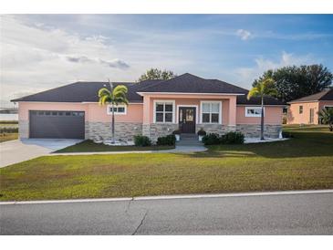 One-story home with peach siding, dark brown garage door, and landscaping at 8243 Alturas Rd, Bartow, FL 33830