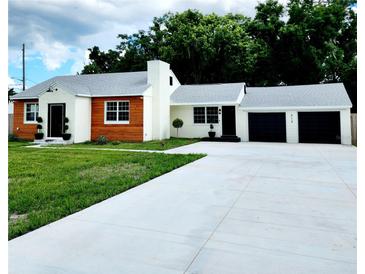 Charming ranch home with white and wood siding, a two-car garage, and a landscaped lawn at 210 W Illiana St, Orlando, FL 32806