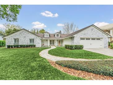 Stunning curb appeal! This home features a stone facade, lush landscaping, and a paved walkway at 7920 Summer Ridge Pl, Orlando, FL 32819