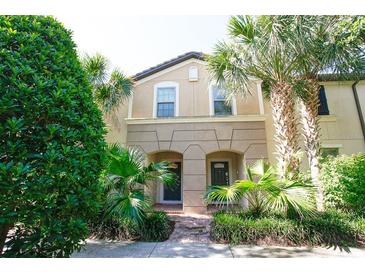 Two story townhome with tan siding, double doors, and lush landscaping at 2022 Majorca Dr, Kissimmee, FL 34747