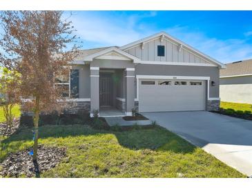 Two-story house with gray siding, stone accents, and a two-car garage at 4248 Sawtooth Ct, Tavares, FL 32778