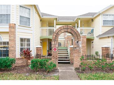 Two-story building with brick arch entryway, lush landscaping, and inviting yellow exterior at 5012 Laguna Bay Cir # 74, Kissimmee, FL 34746