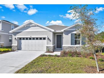 One-story home with gray siding, stone accents, and a two-car garage at 4063 Bannock Ave, Tavares, FL 32778