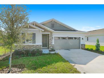 One-story home with stone and siding exterior, two-car garage, and landscaped lawn at 4252 Sawtooth Ct, Tavares, FL 32778