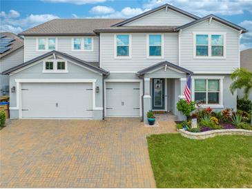 Two-story house with gray siding, three-car garage, and landscaped yard at 2867 Matera Dr, St Cloud, FL 34771