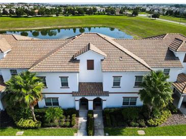 Aerial view of townhouses with Spanish tile roofs and a pond at 8971 Stinger Dr, Davenport, FL 33896