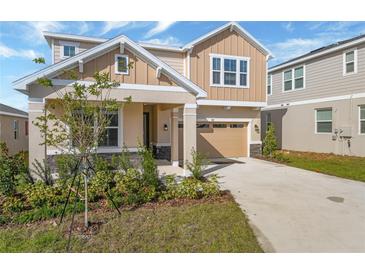 Two-story house with a beige exterior, two-car garage, and landscaping at 812 Griffon Ave, Lake Alfred, FL 33850