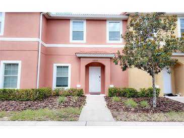 Two-story townhome with peach-colored exterior, walkway, and landscaping at 3006 Red Ginger Rd, Kissimmee, FL 34747