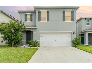 Two-story house with gray siding, white garage door, and landscaping at 6728 Huntleigh Hammock Rd, Harmony, FL 34773