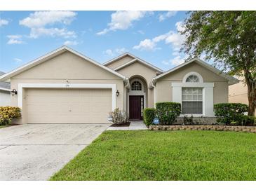Tan one-story house with a two-car garage and landscaped yard at 170 Thornbury Dr, Kissimmee, FL 34744