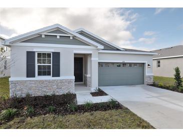 One-story home with gray siding, stone accents, and a two-car garage at 4244 Sawtooth Ct, Tavares, FL 32778