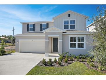 Two-story house with light beige siding, gray shutters, and a two-car garage at 308 Alexandrite St, Deland, FL 32720