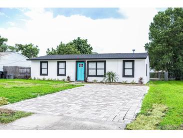 Newly renovated home with a modern exterior, paver driveway, and lush lawn at 1411 Overdale St, Orlando, FL 32825