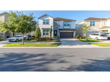 Two-story house with stone accents, a large garage, and landscaping at 9032 Flamingo Key Way, Kissimmee, FL 34747