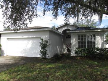 One-story house with a white exterior, attached garage and manicured lawn at 216 Balmoral Ct, Davenport, FL 33896