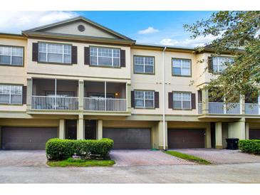 Tan townhome with dark brown garage doors and screened porch at 2532 Grand Central Pkwy # 18, Orlando, FL 32839