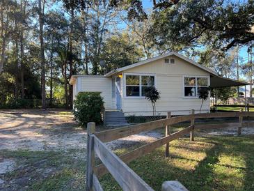 Cute yellow house with a wooden fence and mature trees at 6790 Bass Hwy, St Cloud, FL 34771