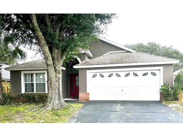 One-story house with a gray exterior, lush landscaping and a white garage door at 2556 Bear Creek Ct, Kissimmee, FL 34747